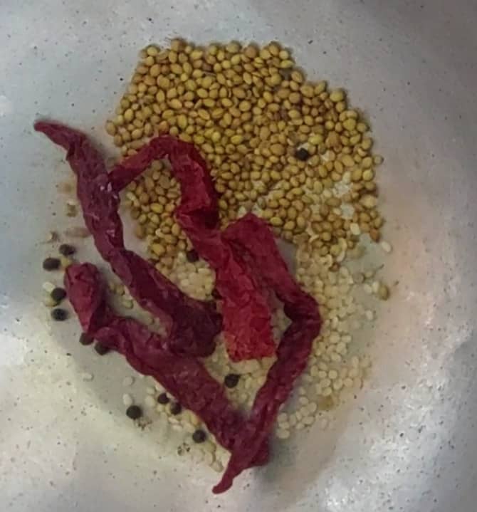 In a pan, add 1 tablespoon of urad dal, 1 tablespoon of coriander seeds, 1/2 teaspoon of peppercorns and 4-5 red chilies.
