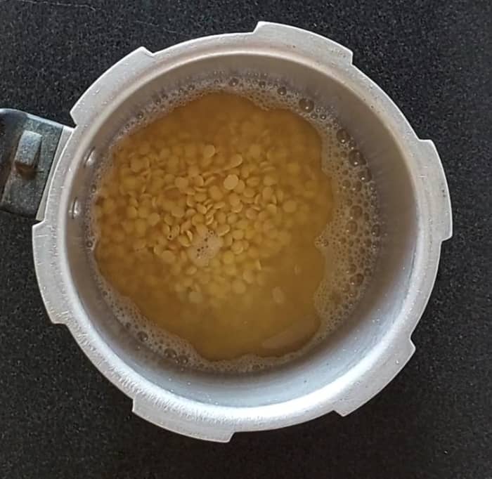 After 30 minutes, transfer the lentils to a cooker, add 1 teaspoon of oil, 1/4 teaspoon salt, close the lid and take 3 whistles or till cooked well. Turn off the flame and let the pressure subside naturally.