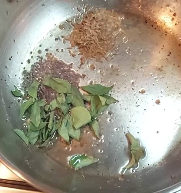 In a pan, heat 2 tablespoons of oil. Add 1/2 teaspoon mustard seeds and 1 teaspoon cumin seeds. Add 1-2 sprigs of curry leaves.