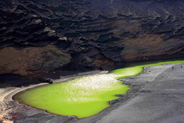 The Green lagoon and black sand of El Golfo. At sunset, the colour of the pool is less bright, but the cliffs take on stunning hues