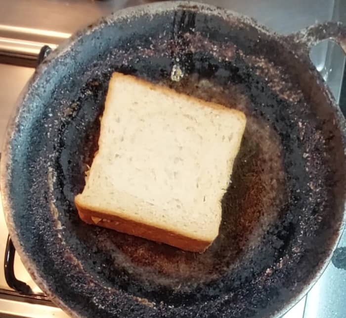 Cover it with another bread slice and press gently. Heat a tawa and sprinkle 1 teaspoon of ghee on the tawa. Place the sandwich on the hot tawa.
