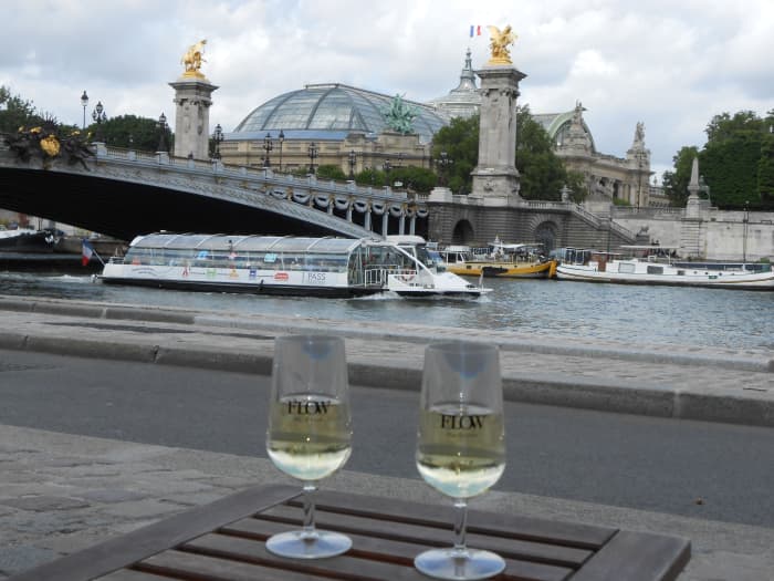 Have a romantic glass of wine together, perhaps like at this outdoor cafe on the banks of the Seine in Paris with the river and a nearby palace as your view.