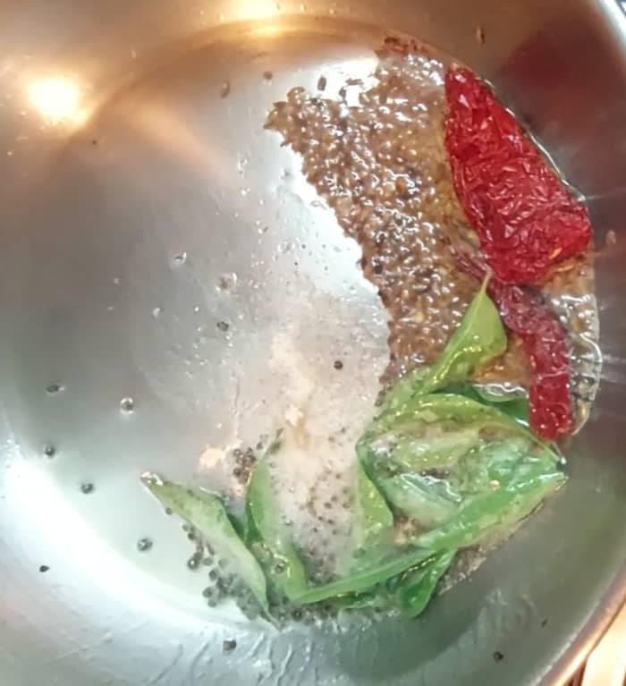 In a pan, heat 2 tablespoons ghee and 2 tablespoons oil. Splutter 1/2 teaspoon mustard seeds and 1 teaspoon cumin seeds. Add 1–2 red chilies, 1–2 sprigs curry leaves and 1/4 teaspoon hing. Fry for a few seconds.