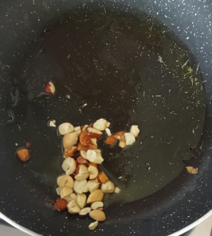 In a pan, heat 1 tablespoon of ghee. Add 1 tablespoon chopped almonds and 1 tablespoon chopped cashews. Fry till light brown and crispy.