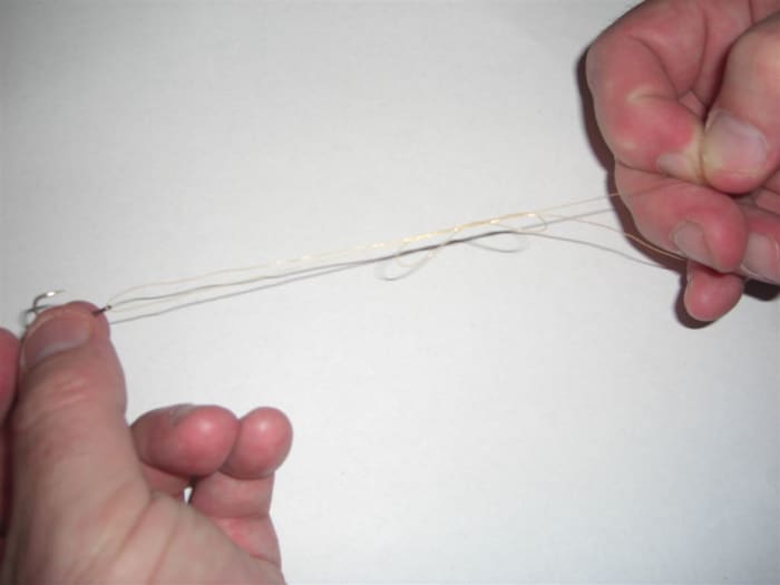 Step 7, holding the hook firmly, and gripping the main line in your right hand, gently pull the free end until the knot begins to come together.