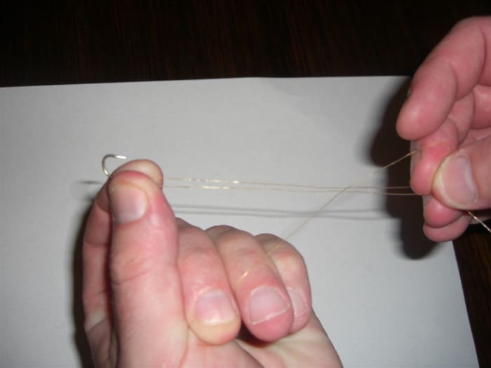 Step 4, holding firmly on to the loops with your right hand, pass the free end of the line behind them.
