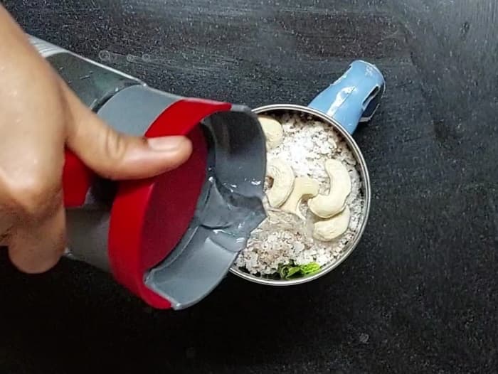 Add 1 cup grated coconut and 5-6 cashews. Add 1/2 cup of water, close the lid and grind to a fine paste.