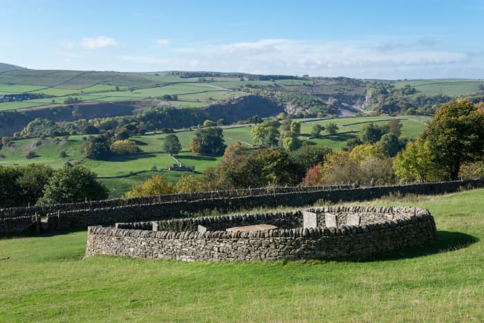 The Riley Graves seen in the field on the left of the road are an important historical site on the outskirts of the 'Plague Village' of Eyam in the Peak District national park.