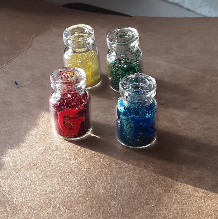 Put glitter in each glass jar! Be sure to choose matching color of glitter for each specific house color.