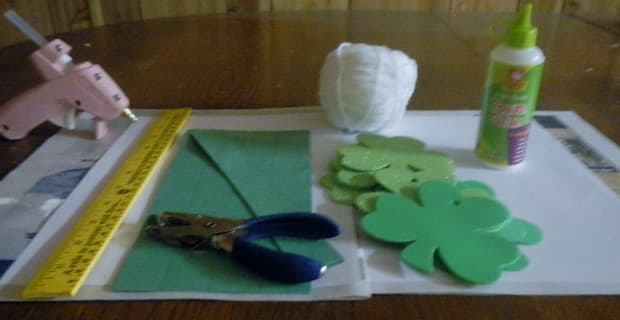 Gather your supplies for your paper garland: yarn, hole punch, colored paper, and shamrock cut-outs and so forth.