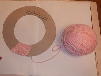 Use hot glue to hold down the end of the yarn and then wrap it around the cardboard, covering it completely.