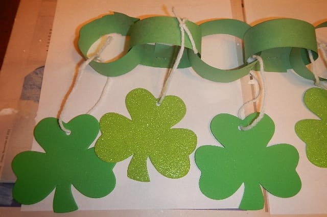 Make paper chains and then use yarn to tie the shamrocks to the individual chains.