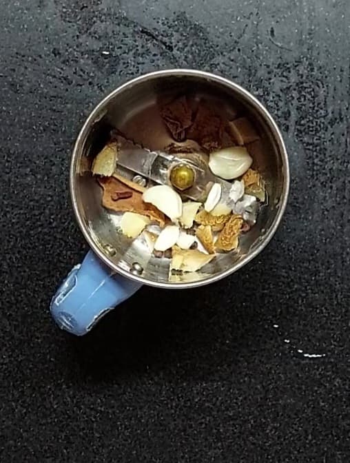 In a mixer jar, add a 2-inch-long cinnamon stick, 2-3 cloves, 8-10 black peppercorns, 2 inches chopped ginger and 5-6 garlic cloves.