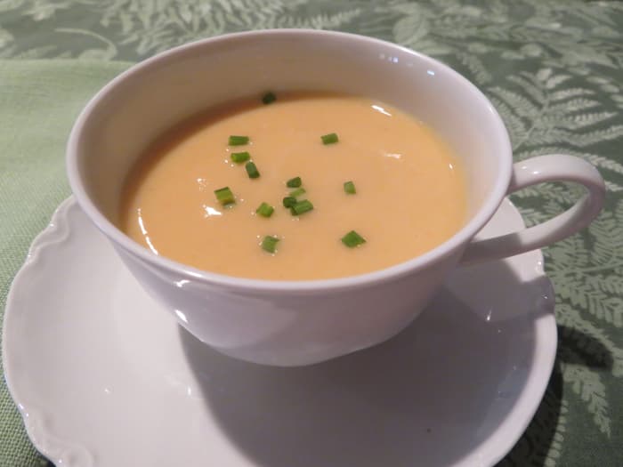 A serving of delicious carrot vichyssoise in a cup topped with snipped chives