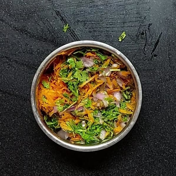 In a bowl, take 1 cup finely chopped onions, 1 cup grated carrots, 1 cup chopped coriander leaves. Add salt and mix well. Set aside.