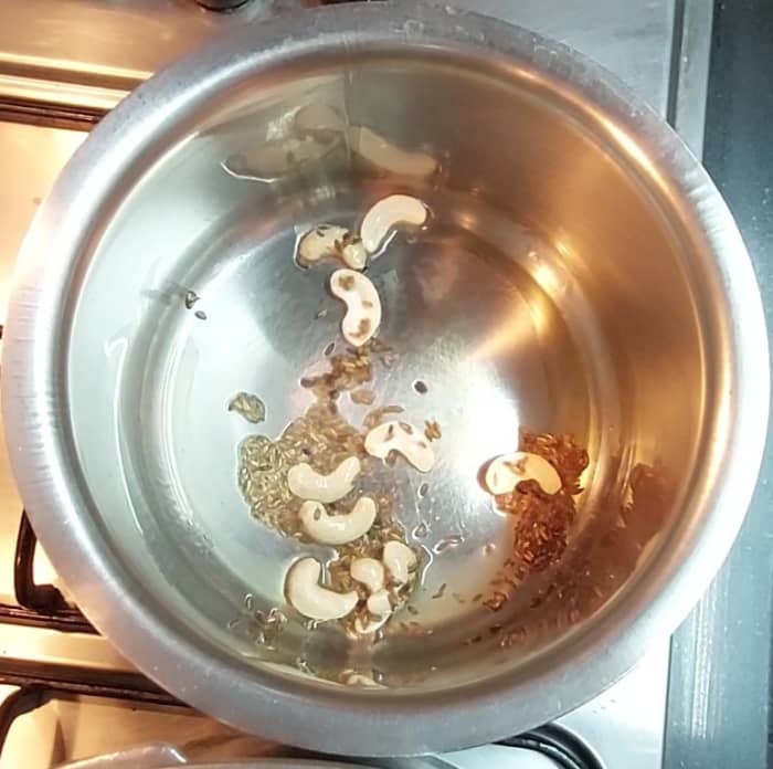 In a pan heat 1 tablespoon ghee and 1 tablespoon oil, splutter 1 teaspoon cumin seeds, add 9-10 cashews, saute till cashews turns golden brown in color.