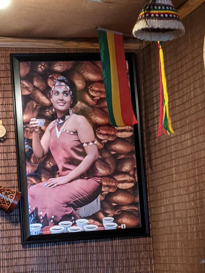 Poster of a model drinking coffee with backdrop of coffee beans. Coffee supposedly originated in Ethiopia and is one of its major exports
