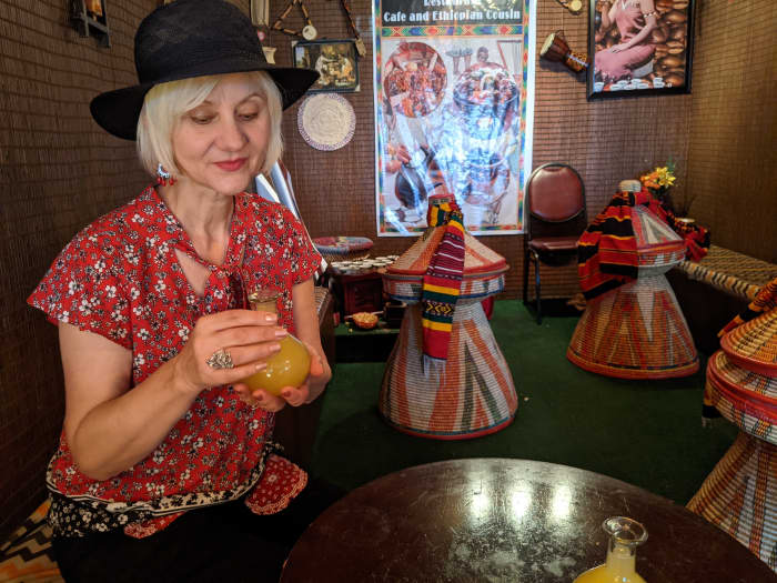 My wife seated at the table and holding the container of Tej (Honey Wine) in which the beverage is served