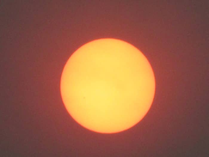 A photo of the sun rising twelve hours later shows no signs of a reddish tint, nor are the edges distinct and clear.