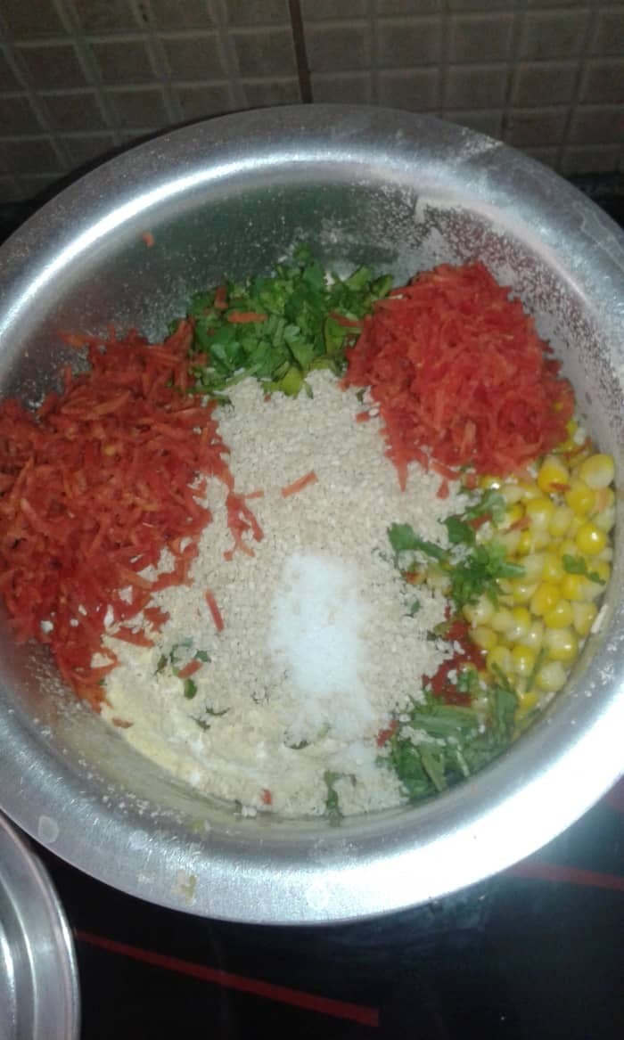 Add rice flour and gram flour. Mix it slightly. Add carrot, coriander, corn, green chilli, ginger-garlic paste, red chilli powder, cumin, sesame seeds and salt.