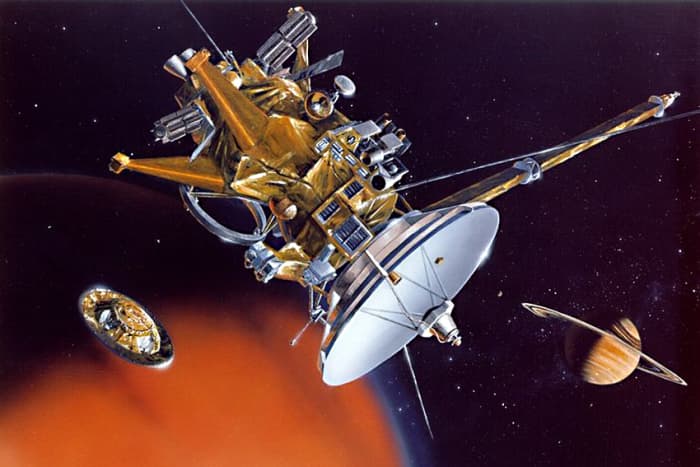 Representation of the Cassini orbiter. On the right is Saturn, and on the left is the great moon Titan. And in the bottom left corner, detached from the orbiter and on its way down to the surface of Titan, is the Huygens probe