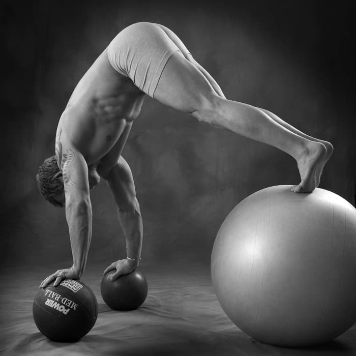 Author doing a push up/hip flexion on ball with hands on medicine ball. This is an advanced exercise that challenges the core muscles as well as the stabilizer muscles around the shoulder joint complex.