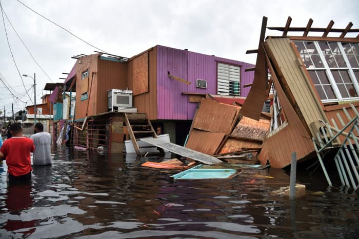 People walk through a flooded street among damaged houses left in the wake of Hurricane Maria in Cataño, Puerto Rico. HECTOR RETAMAL/AGENCE FRANCE-PRESSE/GETTY IMAGES