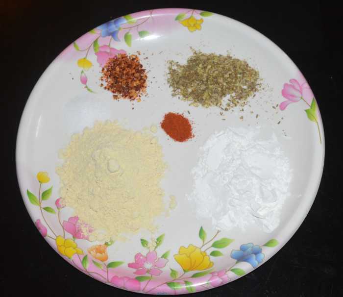 Add gram flour, cornflour, crushed cumin-coriander seeds, chili flakes, red chili powder, and salt.