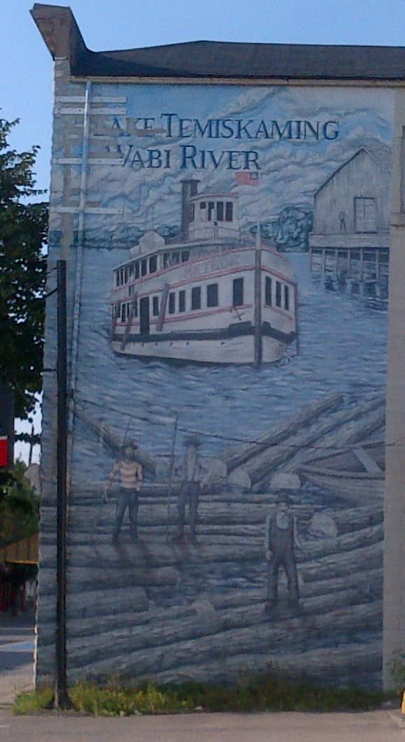 Photograph of the mural on the side of a building on Armstrong Street, New Liskeard, Ontario, Canada, just south of the Wabi River. Photo taken in August 2018.