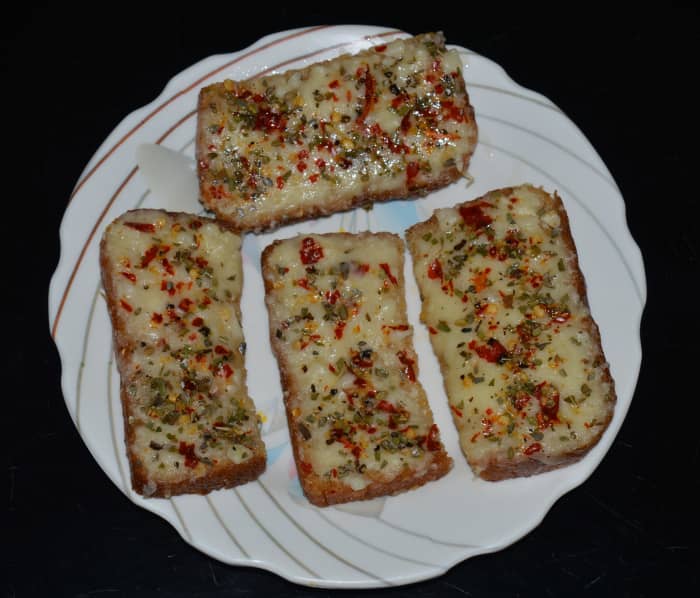 Step three: Grill the slices in the oven for 4-5 minutes. I used a convection oven. It took 4 minutes to grill. Remove, and place the slices on a serving plate. Cheese garlic bread is ready! Serve them hot with tomato sauce.