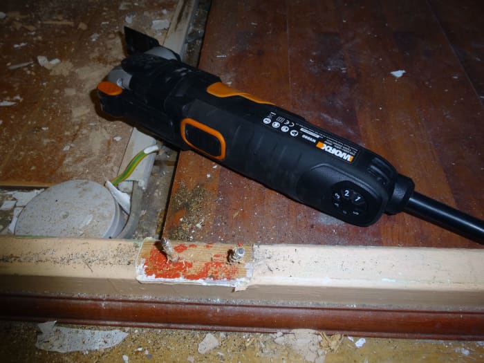 Using my SoniCrafter to cut the protruding nails, after the middle strut of the doorframe had been removed.