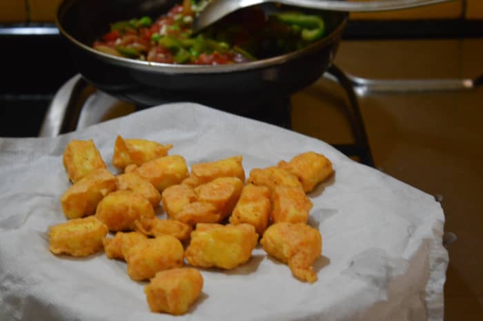 Step two: Add all-purpose flour, cornflour, red chili powder, and salt to a mixing bowl. Prepare a thin liquid batter by adding water. Dip the paneer pieces in it. Fry them in the oil until they become golden brown. Remove and keep them aside.