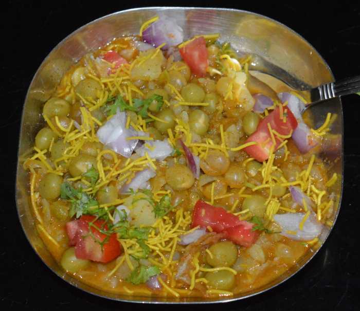 Add 4-6 tablespoons of the gravy on it. Top it with chopped onions, tomatoes, fresh coriander leaves and thin sev. Serve hot. Enjoy this healthy and delightful snack in the evening!