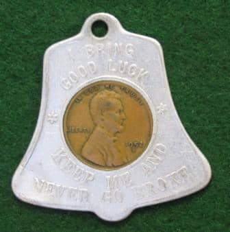 1952-D cent inside a bell-shaped holder. The obverse reads, “I BRING GOOD LUCK/KEEP ME AND NEVER GO BROKE.” The hole at the top allows it to be used as a key chain fob.