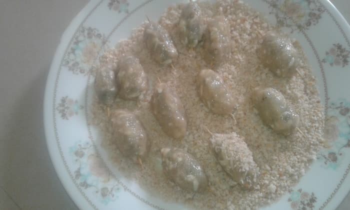 Wet your palms with water, take a small portion of the mince, spread it on your palm and place a rolled chutney over it. Coate the rolled chutney with the mince. Shape it properly and keep it over the breadcrumbs.