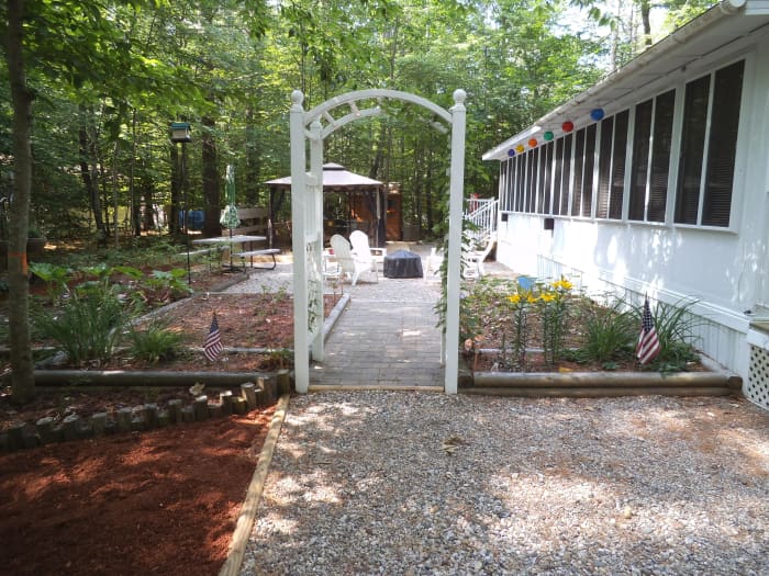 The vinyl garden archway with planting beds on each side. This defines the entertainment area of our yard. There's the firepit and the gazebo just beyond.