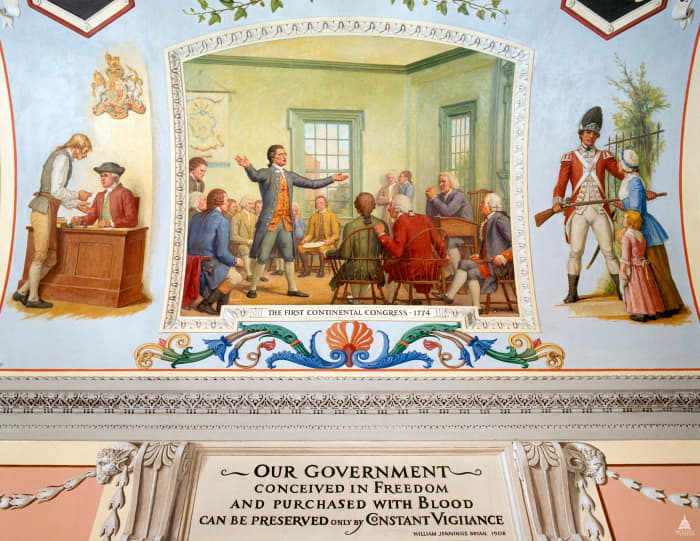 Mural from the U.S. Capitol building. The left painting shows a colonist paying taxes. The center painting shows debate among the delegates during the First Continental Congress. The right painting shows a British solider blocking the path of a woman