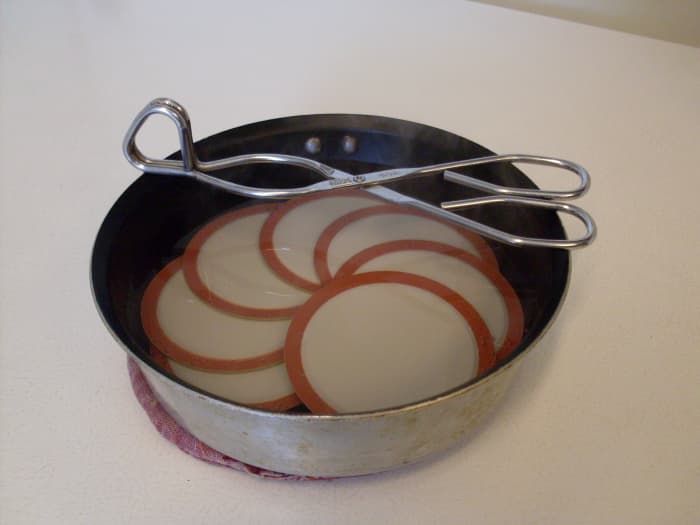 Either gently simmer the lids (don't boil!), or set them in a small pan and pour on boiling water to cover, to scald them.