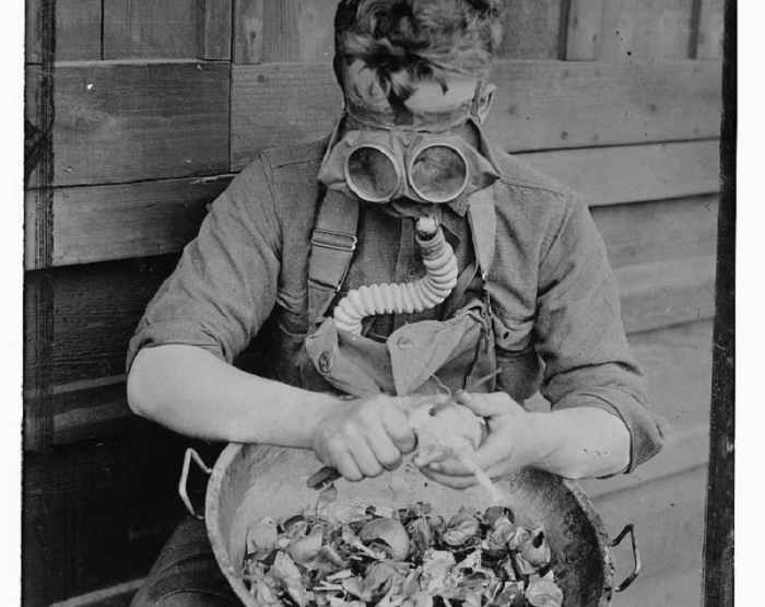 A soldier peeling onions at Camp Kearny wears an "anti-onion" gas mask. 1917