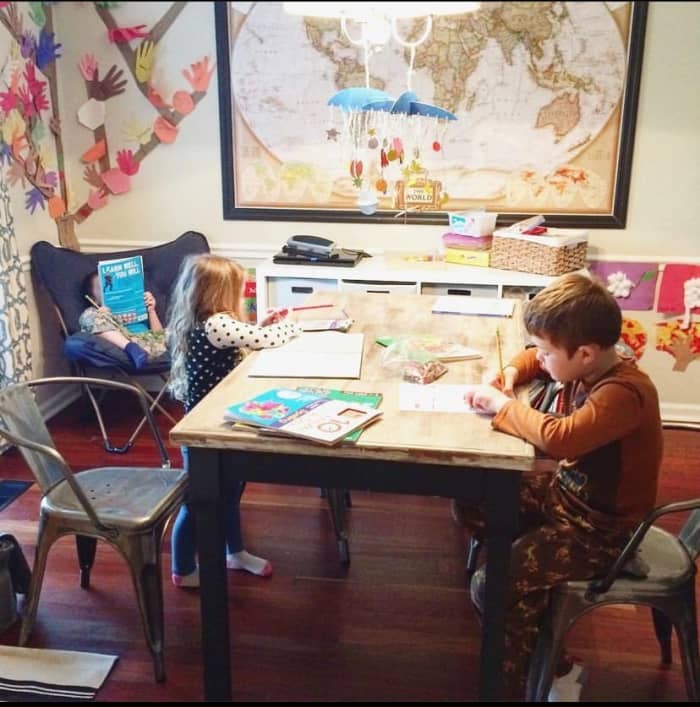 Older students are busy with workbooks while the preschooler works on an activity from her busy box.