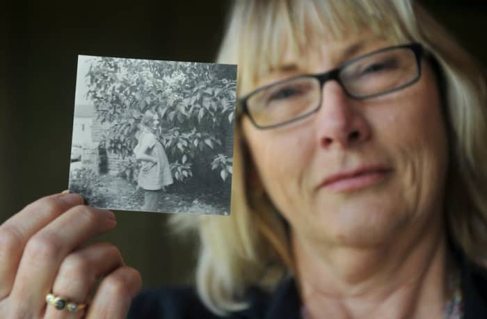 At 18, Australian women, Linda Miles was forced to give up her child for adoption. She is holding a picture of when she was pregnant.