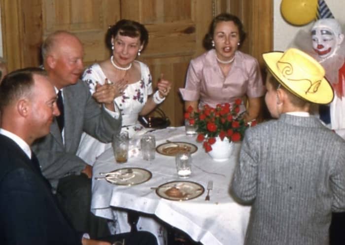 The Eisenhower family gathers for a birthday party. From left to right round the table: John Eisenhower, Dwight Eisenhower, Mamie Eisenhower, Barbara Eisenhower, unidentified clown, David Eisenhower with back to camera.