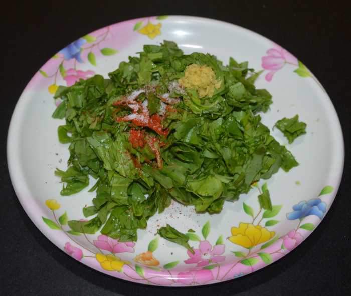 Step two: For making the stuffing, mix chopped spinach, red chili powder, carom seeds, and grated ginger.