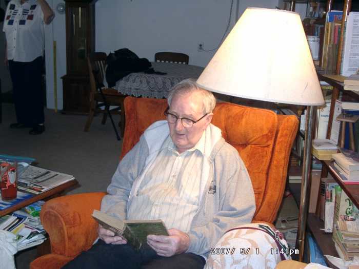 The lamp sheds plenty of light which older eyes need. A sweater or sweatshirt are his choice for keeping warm while reading. A table next to his chair gives him a place to keep his book at hand.
