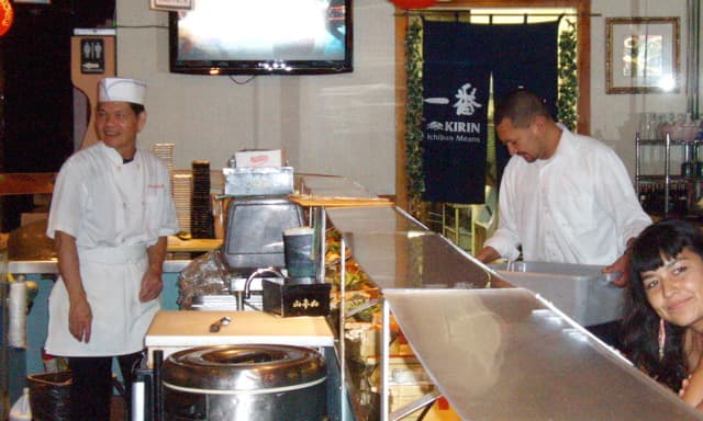 Taking a quick break, one of the cooks watches too. Note the glass counter above the boat run. This is where the cooks place special orders.