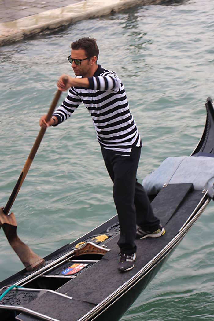 A gondolier plies his trade, navigating the canals of Venice just as his predecessors have done for hundreds of years