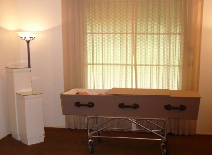 Sarah in casket in viewing room waiting for transport to grave.