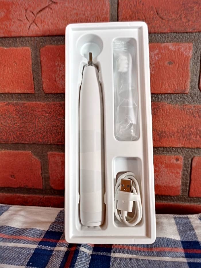 The package contains the toothbrush, USB charging cord, user's guide, and a brush
