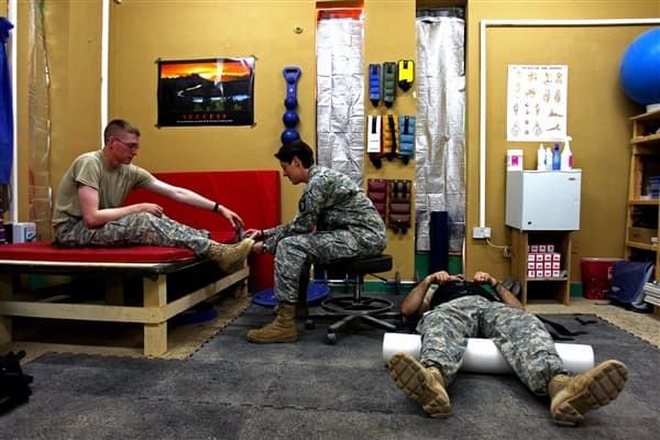 Army Staff Sgt. Gaither, physical therapy noncommissioned officer in charge with 1st Brigade Combat Team, 101st Airborne Division, checks on a soldier with back pain at the combat support hospital at Contingency Operating Base Speicher, Iraq.
