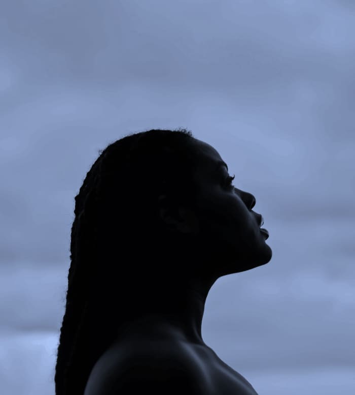 A woman looks to the sky at dusk as she waits patiently for stars to appear.